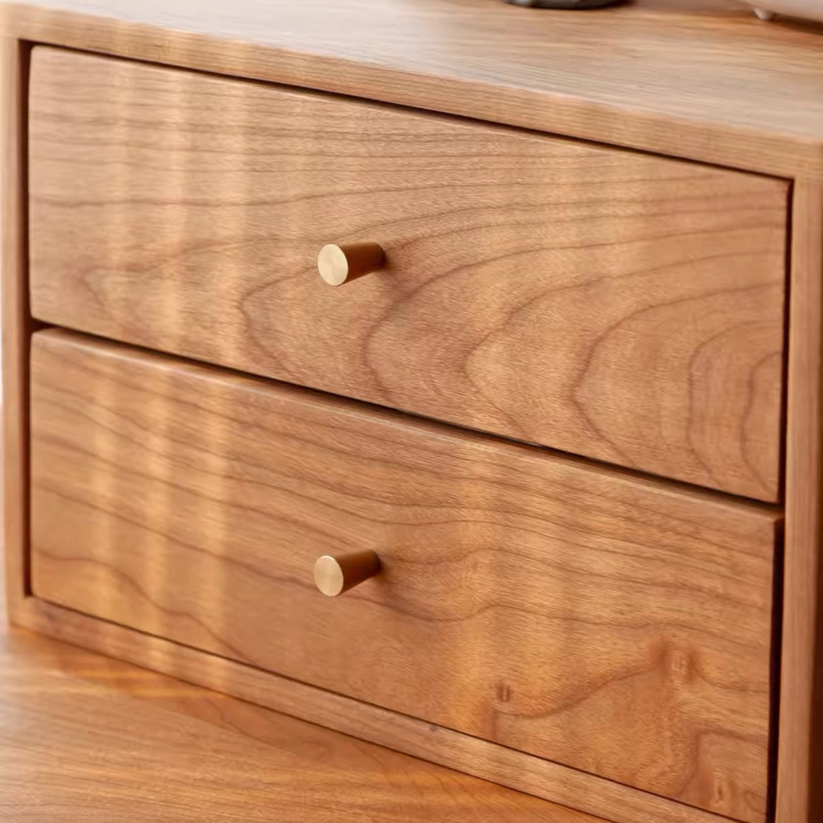 Close-up of a wooden two-drawer cabinet with a warm medium brown finish and small round light wood knobs, set against a matching wood background.