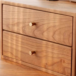 Close-up of a wooden two-drawer cabinet with a warm medium brown finish and small round light wood knobs, set against a matching wood background.