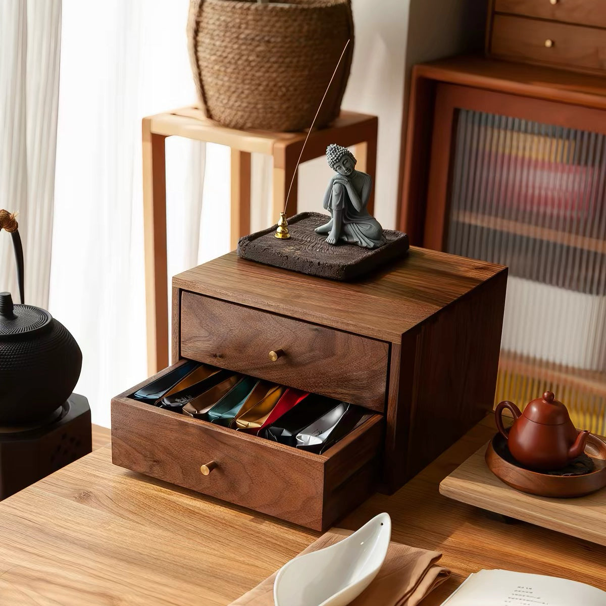 A dark brown wooden desktop organizer with two drawers, styled in a warm, minimalist room setting with a small Buddha statue on top.