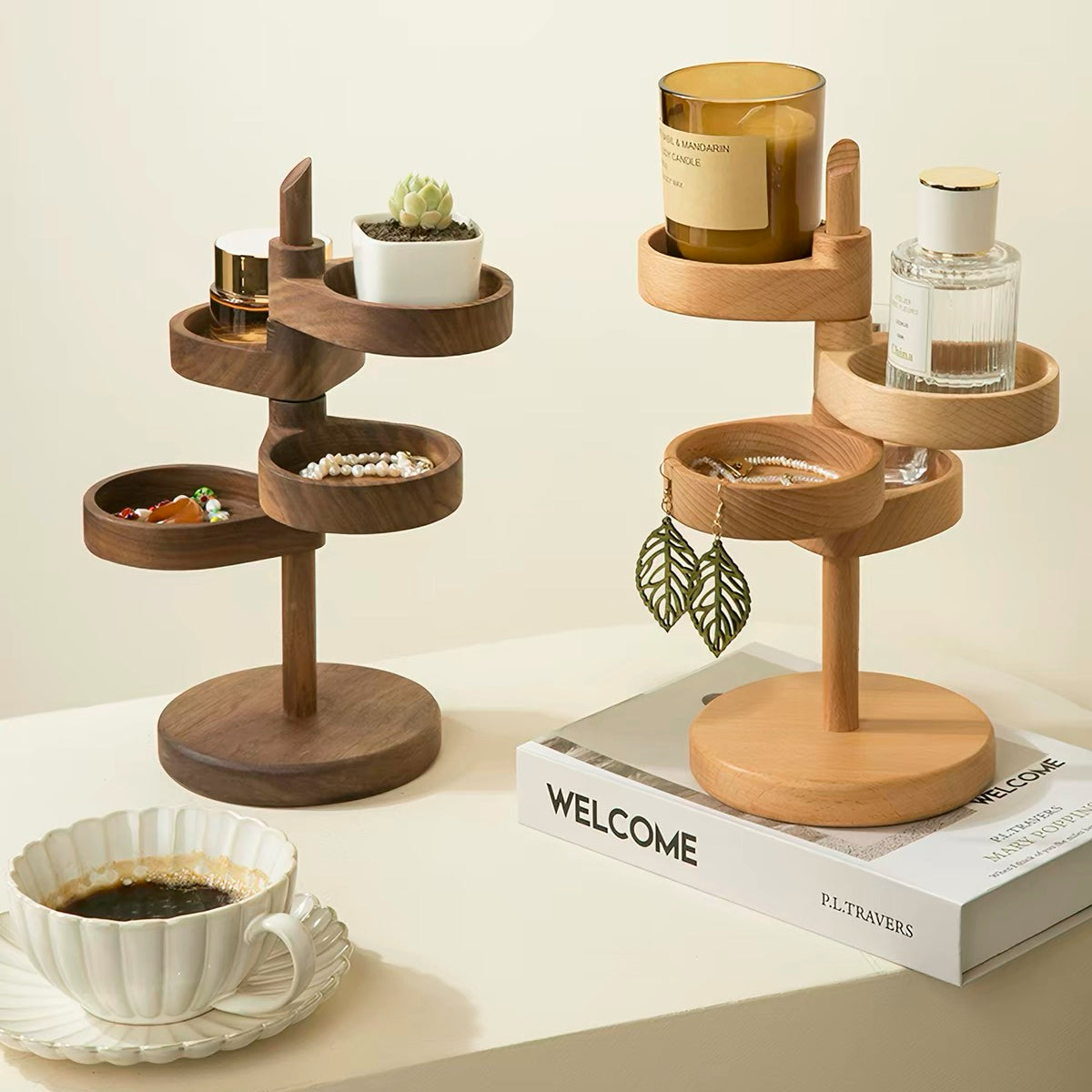 Two wooden tiered jewelry organizers styled on a cream tabletop with props, including a candle, perfume bottle, earrings, and a coffee cup.