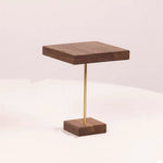 A modern square wooden tabletop on a slim gold metal stand, set against a clean, light beige background.