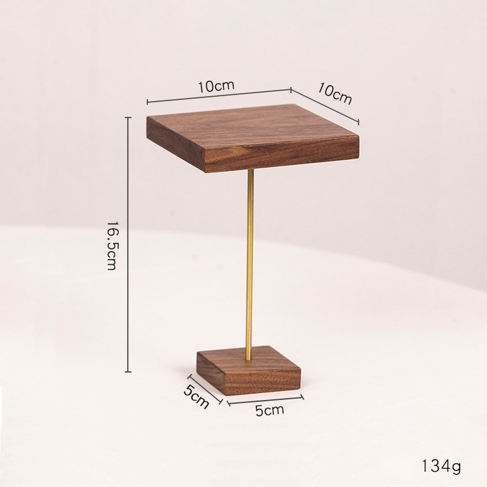 A small wooden tabletop display stand with a square dark wood top and base, a slim gold metal center rod, and dimension callouts showing 10 cm top, 16.5 cm height, 5 cm base, and 134 g weight on a light neutral background.