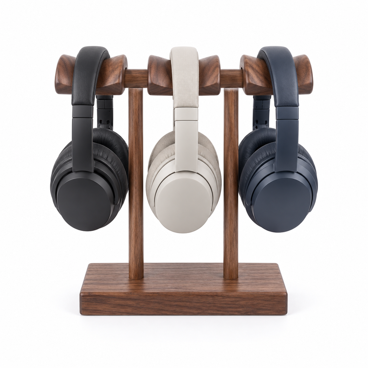 Three over-ear headphones displayed on a wooden stand against a white background: one black, one light beige, and one dark blue-gray.