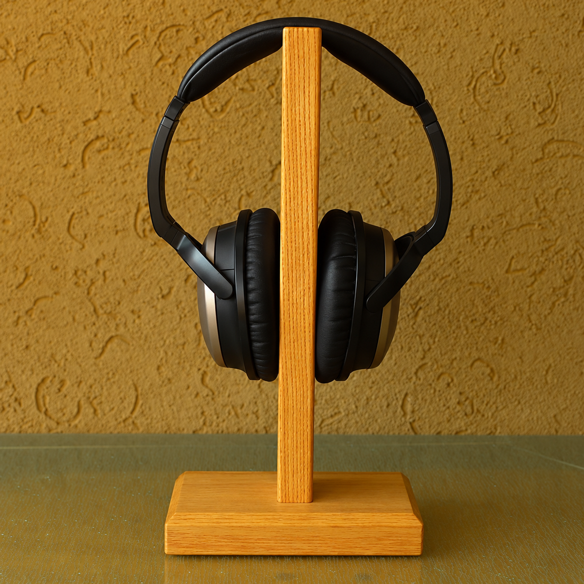 Black over-ear headphones displayed on a light wood stand against a textured mustard-yellow wall.