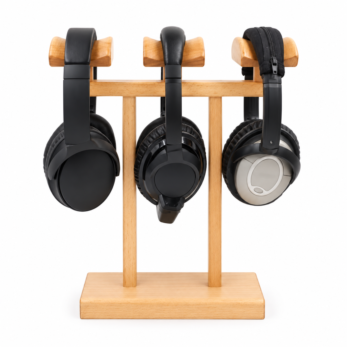 Three over-ear headphones displayed on a light wood headphone stand against a plain white background.