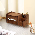 A dark brown wooden desk organizer with a tissue dispenser and pen holder, shown on a light gray desk with a cup nearby.