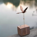 Wooden bird sculpture on a block with a blurred natural background